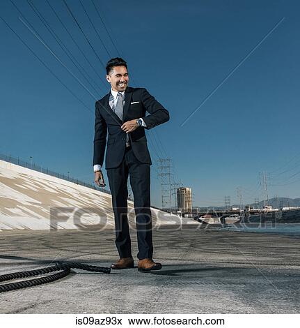 Stock Photo - Businessman looking away smiling, Los Angeles river, California, USA. Fotosearch