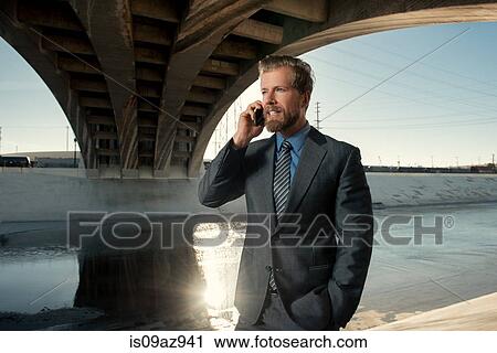 Stock Image - Businessman making telephone call, Los Angeles river, California, USA. Fotosearch
