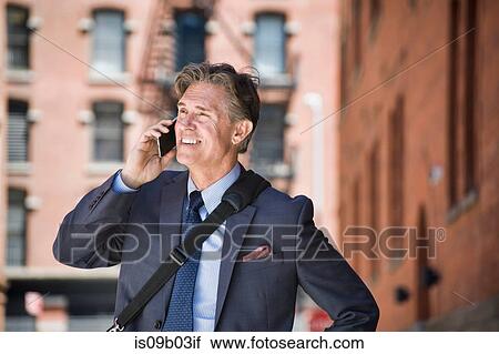 Businessman outdoors, using smartphone, smiling View Large Photo Image Stock Image - Businessman outdoors, using smartphone, smiling. Fotosearch