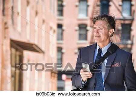 Businessman outdoors, using smartphone View Large Photo Image Stock Image - Businessman outdoors, using smartphone. Fotosearch