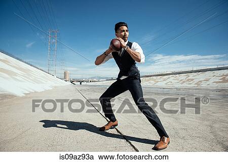 Stock Image - Businessman playing american football on Los Angeles river, California, USA. Fotosearch