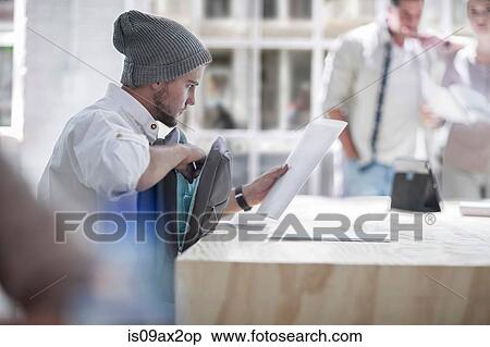 Stock Photography - Businessman reading document in loft office. Fotosearch