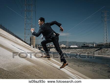 Businessman running up riverbank, Los Angeles river, California, USA View Large Photo Image Picture - Businessman running up riverbank, Los Angeles river, California, USA. Fotosearch