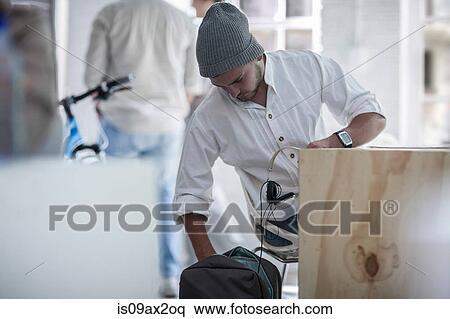 Businessman settling in at desk in loft office View Large Photo Image Stock Photography - Businessman settling in at desk in loft office. Fotosearch