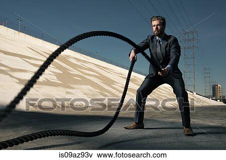 Stock Photo - Businessman using gym ropes, Los Angeles river, California, USA. Fotosearch
