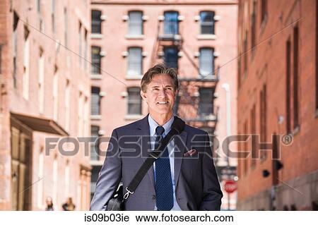Businessman walking outdoors, smiling View Large Photo Image Stock Image - Businessman walking outdoors, smiling. Fotosearch