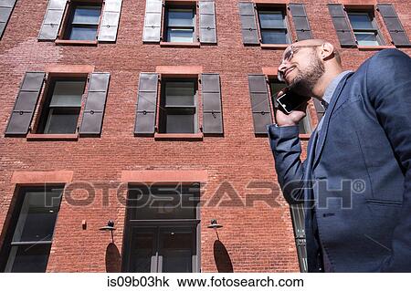 Businessman walking outdoors, using smartphone, low angle view View Large Photo Image Stock Image - Businessman walking outdoors, using smartphone, low angle view. Fotosearch