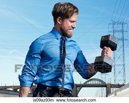 Picture - Businessman weightlifting, Los Angeles river, California, USA. Fotosearch