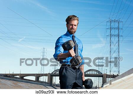 Stock Image - Businessman weightlifting, Los Angeles river, California, USA. Fotosearch