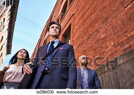 Stock Image - Businessmen and women walking outdoors, low angle view. Fotosearch