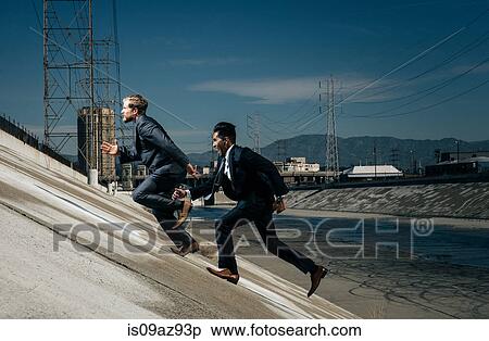 Businessmen running up riverbank, Los Angeles river, California, USA View Large Photo Image Stock Photography - Businessmen running up riverbank, Los Angeles river, California, USA. Fotosearch