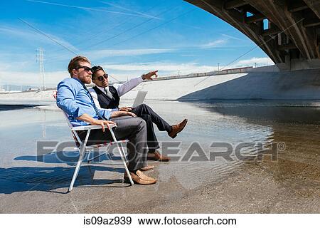 Businessmen sitting in deckchairs on Los Angeles river, California, USA View Large Photo Image Stock Photo - Businessmen sitting in deckchairs on Los Angeles river, California, USA. Fotosearch