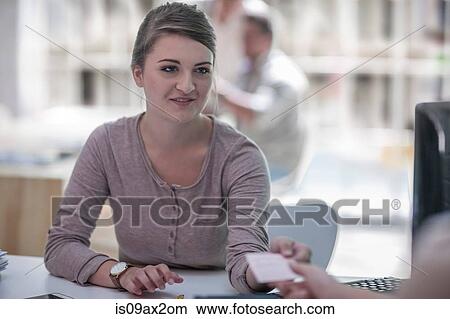 Businesswoman giving card to colleague in office View Large Photo Image Picture - Businesswoman giving card to colleague in office. Fotosearch