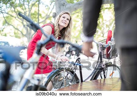 Businesswoman locking bicycle whilst meeting businessman in park View Large Photo Image Stock Photograph - Businesswoman locking bicycle whilst meeting businessman in park. Fotosearch