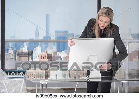 Stock Photo - Businesswoman setting up computer in office. Fotosearch