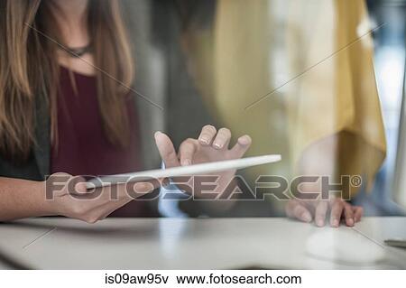 Businesswoman sitting at desk, using digital tablet, mid section View Large Photo Image Stock Photo - Businesswoman sitting at desk, using digital tablet, mid section. Fotosearch