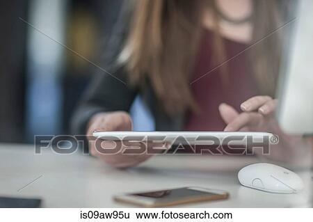 Businesswoman sitting at desk, using digital tablet, mid section View Large Photo Image Stock Photograph - Businesswoman sitting at desk, using digital tablet, mid section. Fotosearch