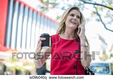 Businesswoman with takeaway coffee talking on cellphone in city View Large Photo Image Stock Photography - Businesswoman with takeaway coffee talking on cellphone in city. Fotosearch