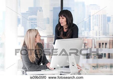 Stock Image - Businesswomen chatting in office. Fotosearch