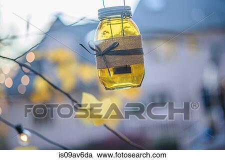 Candlelit jar hanging from twig outside house at dusk View Large Photo Image Stock Image - Candlelit jar hanging from twig outside house at dusk. Fotosearch