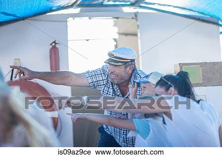 Stock Image - Captain with tourists pointing on boat trip, Cape Town, South Africa. Fotosearch