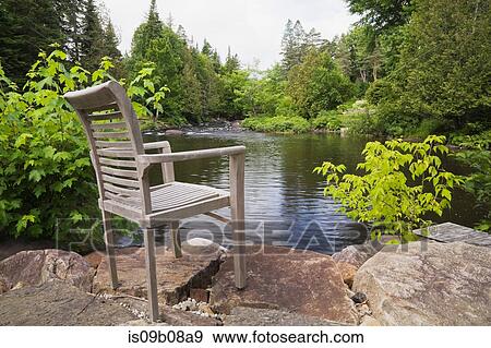 Stock Photo - Chair on rocks by lake. Fotosearch