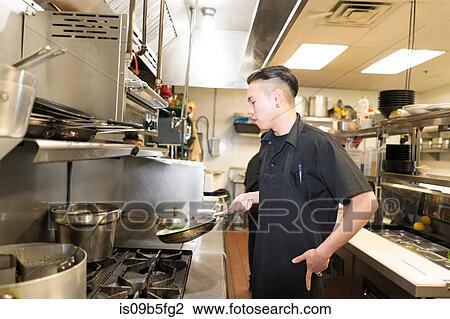 Stock Image - Chef cooking in commercial kitchen. Fotosearch