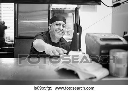 Stock Photography - Chef in commercial kitchen smiling at camera. Fotosearch