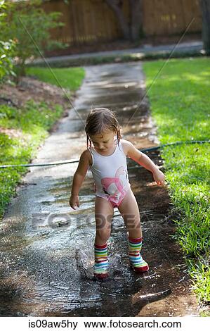Child in wellies playing in puddle of water View Large Photo Image Stock Photo - Child in wellies playing in puddle of water. Fotosearch