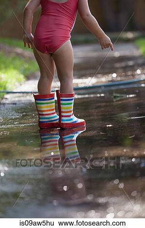 Child in wellies playing in puddle of water View Large Photo Image Stock Photograph - Child in wellies playing in puddle of water. Fotosearch