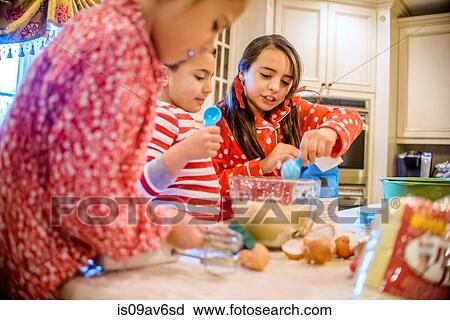 Stock Image - Children in kitchen wearing pyjamas baking. Fotosearch