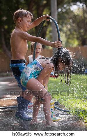 Stock Photography - Children playing with water hose on sidewalk. Fotosearch