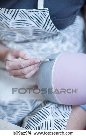 Picture - Close up of female potter's hands painting glaze onto vase in workshop. Fotosearch
