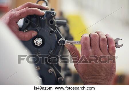 Close up of male hands repairing outboard motor in boat repair workshop View Large Photo Image Picture - Close up of male hands repairing outboard motor in boat repair workshop. Fotosearch