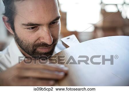Stock Image - Close up of man inspecting chopping board in factory. Fotosearch