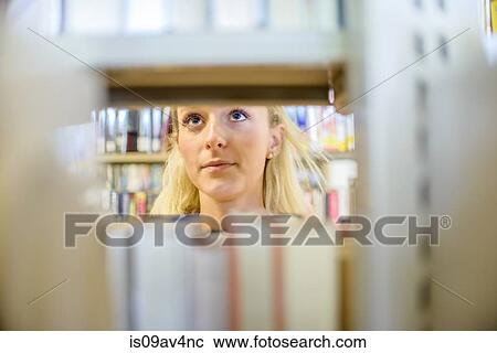 Close up of young woman behind book shelves in library View Large Photo Image Stock Image - Close up of young woman behind book shelves in library. Fotosearch