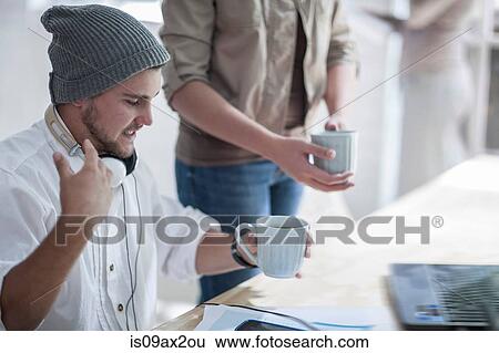 Colleague handing out coffee in loft office View Large Photo Image Stock Photograph - Colleague handing out coffee in loft office. Fotosearch