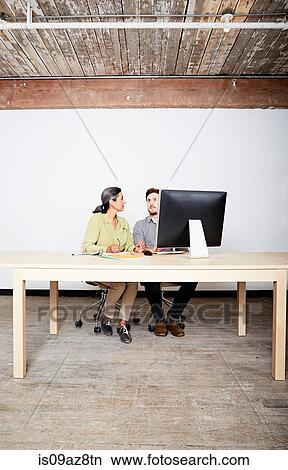 Colleagues at desk behind computer monitor View Large Photo Image Picture - Colleagues at desk behind computer monitor. Fotosearch