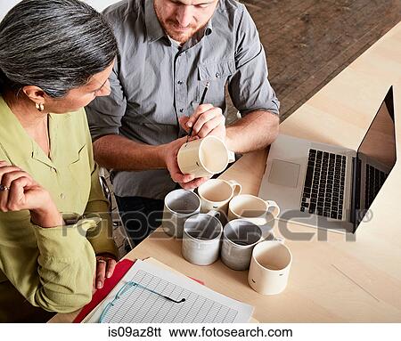 Colleagues at desk discussing pottery mugs View Large Photo Image Stock Photograph - Colleagues at desk discussing pottery mugs. Fotosearch