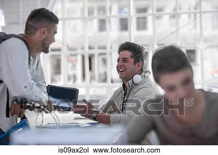 Colleagues chatting in office, woman working in foreground View Large Photo Image Stock Image - Colleagues chatting in office, woman working in foreground. Fotosearch