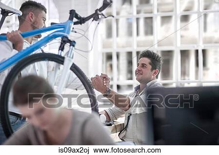 Stock Image - Colleagues greeting with power handshake in office. Fotosearch