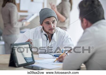 Stock Photo - Colleagues having discussion in loft office. Fotosearch