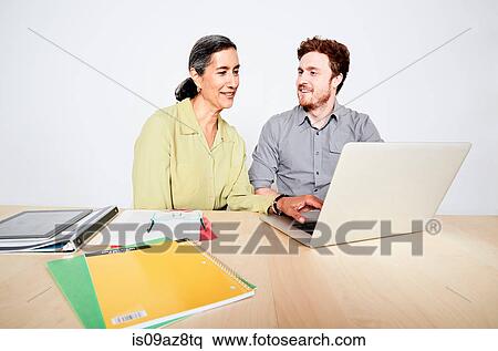 Colleagues looking at computer monitor smiling View Large Photo Image Stock Photography - Colleagues looking at computer monitor smiling. Fotosearch