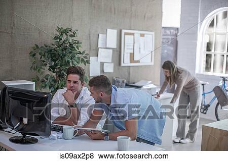 Colleagues working at computer in loft office View Large Photo Image Stock Photo - Colleagues working at computer in loft office. Fotosearch
