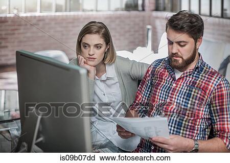 Couple at home, looking at computer screen, man holding paperwork View Large Photo Image Stock Image - Couple at home, looking at computer screen, man holding paperwork. Fotosearch