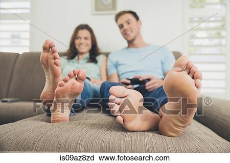 Couple barefoot on sofa using video game controller View Large Photo Image Stock Image - Couple barefoot on sofa using video game controller. Fotosearch
