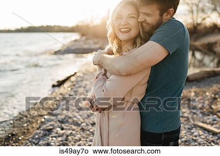 Couple beside lake, man hugging woman View Large Photo Image Picture - Couple beside lake, man hugging woman. Fotosearch