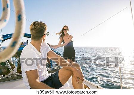 Stock Image - Couple chatting on sailboat, San Diego Bay, California, USA. Fotosearch
