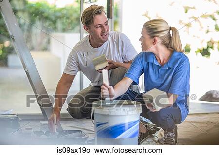 Couple crouching stirring bucket of paint View Large Photo Image Picture - Couple crouching stirring bucket of paint. Fotosearch