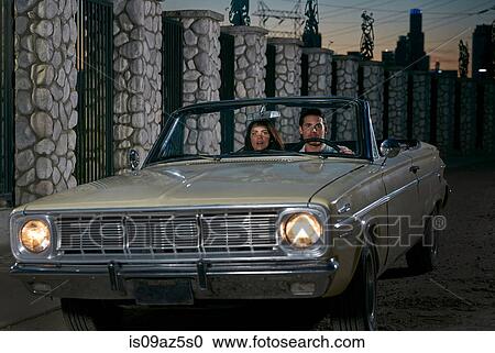 Stock Image - Couple driving convertible classic car at night, Los Angeles, California, USA. Fotosearch